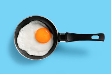 Mavi arka planda leziz kızarmış yumurta ile kızartma tavası.