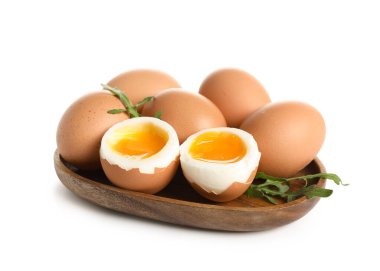 Kaynamış yumurta ve beyaz arka planda roka yapraklı ahşap tabak.