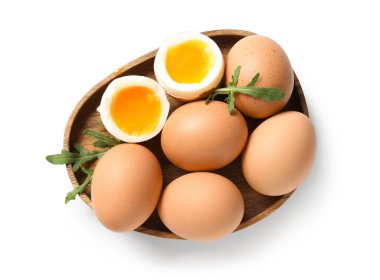 Kaynamış yumurta ve beyaz arka planda roka yapraklı ahşap tabak.