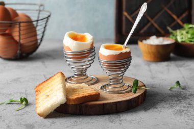 Yumuşak yumurta ve gri arka planda ekmek dilimleri olan tutucular.
