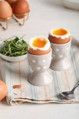 Kaynamış yumurta ve beyaz ahşap arka planda mikro yeşil tutucular.