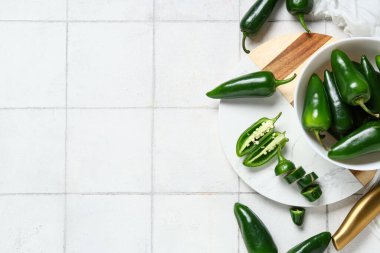 Beyaz fayanslı yeşil biberli kase ve kesim tahtası.