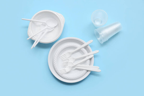 Composition with plastic tableware and cutlery on pink background