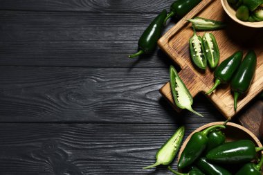 Siyah ahşap arka planda yeşil biberli kase ve kesim tahtaları