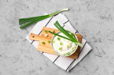 Bir kase lezzetli ekşi krema ve arka planda yeşil soğan.