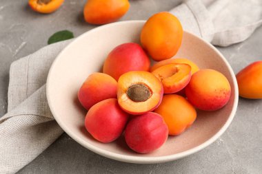 Gri arka planda tatlı kayısıları olan bir kase