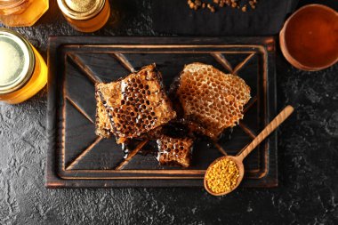 Tatlı bal, taraklar ve siyah arkaplanda arı poleni