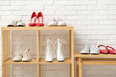 Dükkandaki tuğla duvarın yanında farklı kadın ayakkabıları olan raf ünitesi.
