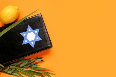 Turuncu arka planda dört tür (lulav, hadas, arava, etrog) Sukkot festival sembolleri ve Tevrat olarak