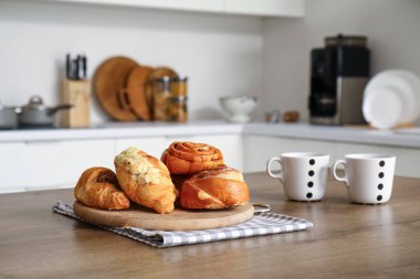 Modern mutfağın ahşap tahtası, lezzetli hamur işleri ve kahve fincanları.