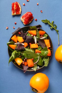 Bir tabak lezzetli salata, hurma, nar tohumu ve mavi arkaplanda soğan.