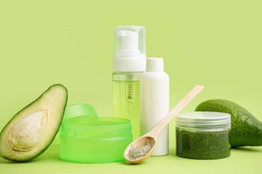 Yeşil zemin üzerinde kozmetik ürünler ve taze avokado seti