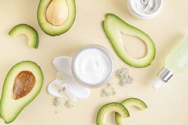 Taze kesilmiş avokado ve bej arka planda bir kavanoz krema ile kompozisyon