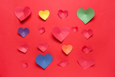 Kırmızı arka planda renkli kağıt kalpler olan kompozisyon. Sevgililer Günü kutlaması
