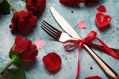 Sevgililer Günü için güzel çatal bıçak takımı. Kırmızı güller, mum ve kalpler mavi grunge arka planda.