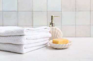 Temiz yumuşak havlu yığını, bir şişe kozmetik ürün ve banyo duvarının yanındaki sabun kalıbı.