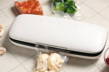 Beyaz karo arka planda et ve sebzeli yiyecekler için vakum mühür makinesi.
