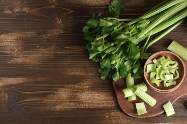 Tahta zemin üzerinde taze yeşil kereviz olan yemek ve kase.