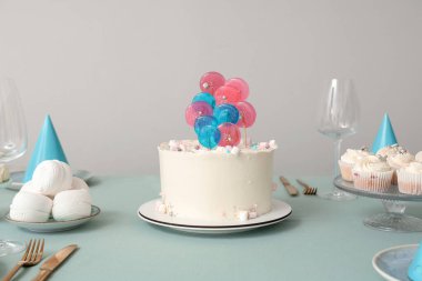 Doğum günü partisi için şekerli pasta ve tabaklar beyaz duvara karşı masada.