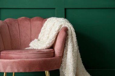 Oturma odasında yeşil duvarın yanında ekoseli rahat bir koltuk.