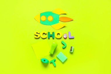 Kağıt roket, yazı okulu ahşap harflerden ve yeşil arka plandaki okul kırtasiyesinden yapılmış.