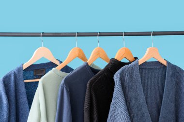 Mavi duvarın yanında kazaklarla dizilin, yakın plan.