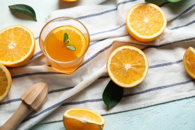 Bir bardak taze portakal suyu naneli ve açık mavi arka planda kesilmiş meyveler.