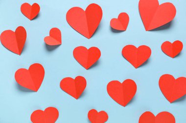 Açık mavi zemin üzerinde kırmızı kağıt kalpler olan kompozisyon. Sevgililer Günü kutlaması
