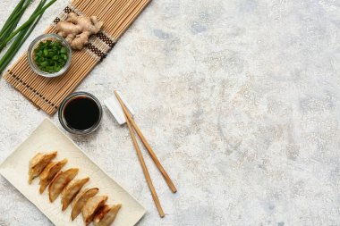 Bir tabak kızarmış Japon gyozası, bir kase soya sosu ve beyaz arka planda yeşil soğan.