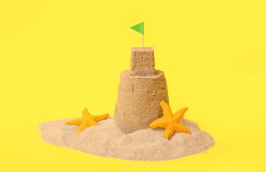 Güzel kumdan kale, sarı arka planda deniz yıldızları.