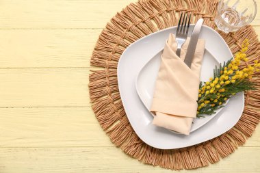 Sarı ahşap arka planda mimoza çiçekleri olan güzel bir masa.