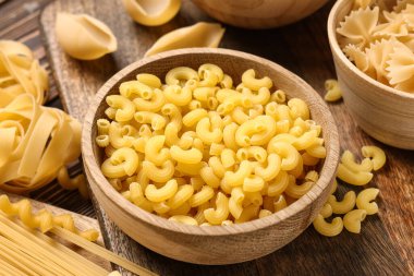 Ahşap arka planda çiğ makarna ile kase, yakın plan