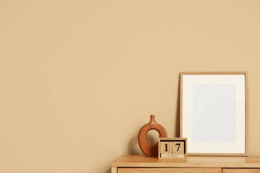 17 AĞUSTOS tarihli küp takvimi ve bej duvarın yanındaki rafta boş çerçeve