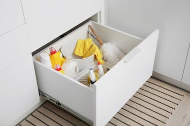 Modern mutfakta temizlik malzemeleri, sepet ve kova dolu çekmece.