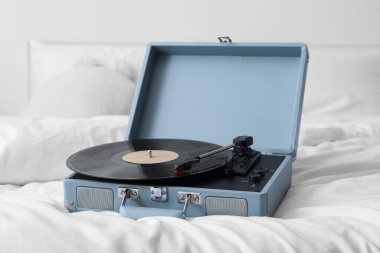 Hafif yatak odasındaki rahat yatağın üzerinde vinil diski olan Retro kayıt çalar, yakın plan