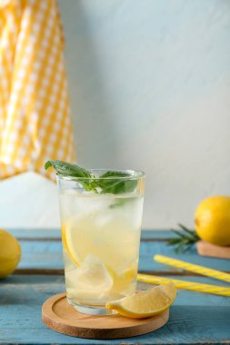 Mavi ahşap masada fesleğen yapraklı bir bardak taze limonata.