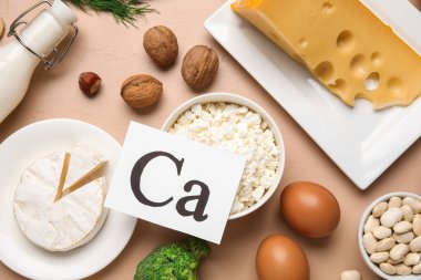 Kalsiyum sembollü kağıt ve bej arka planda sağlıklı ürünler