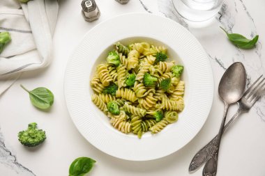 Brokolili lezzetli fusilli makarna ve beyaz arka planda bir bardak su.