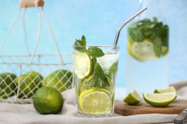 Bardak ve bir şişe taze mojito kokteyli ve beyaz masada nane şekeri.