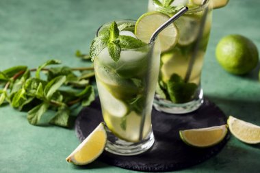 Yeşil arka planda taze mojito kokteyli ve naneli, yakın plan.