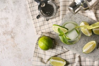Beyaz grunge arka planında bir bardak lezzetli mojito, peçete ve kesim tahtası ile kompozisyon