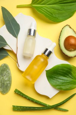 Kozmetik ürünleri şişeleri, sıva podyum ve sarı arka planda malzemeler içeren kompozisyon, yakın plan
