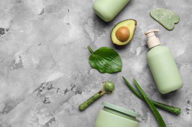 Gri grunge arka planda bileşenleri, yüz masajı araçları, şişeler ve kozmetik ürünlerin kavanozları, yakın çekim