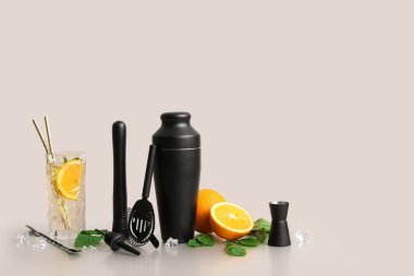 Barmen aletleriyle kompozisyon, lezzetli kokteyllerle bardak ve beyaz arka planda malzemeler.