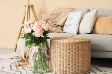 Gri kanepeli, sehpalı ve vazosunda güzel şakayıklar olan şık bir oturma odası.