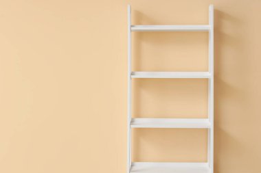 Bej duvarın yanında boş beyaz kitaplık