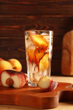 Tahta zemin üzerinde kekik olan bir bardak taze şeftalili limonata.