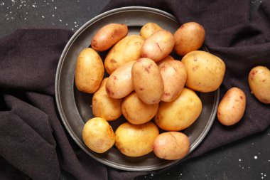 Siyah arka planda çiğ patates tabağı.