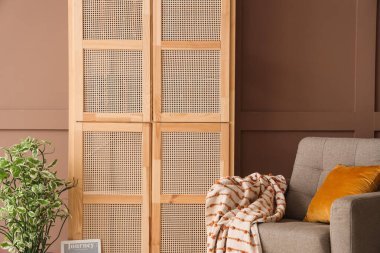 Odanın içindeki kahverengi duvarın yanında ahşap dolap ve rahat koltuk, yakın plan.