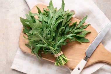 Gri arka planda taze roka yaprakları olan ahşap tahta tahta.